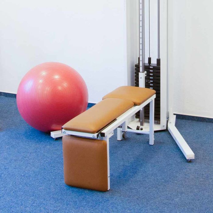 Ein Sportbank und ein roter Gymnastikball im Behandlungszimmer von Pawel's Physiotherapie-Praxis.
