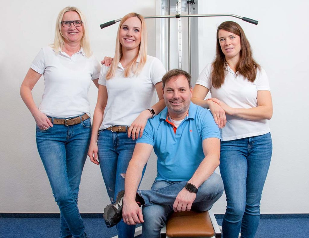 Das Team der Physiotherapiepraxis Pawel's Physio in Witten vor einem krankengymnastischen Seilzug-Trainingsgerät.